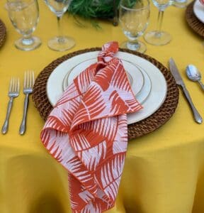 mango tablecloth with a salmon-pink leaf print napkin draped over the setting