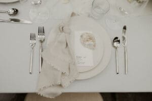 top view of the place setting: a shell and a knotted cloth draped over nested plates with silverware on either side
